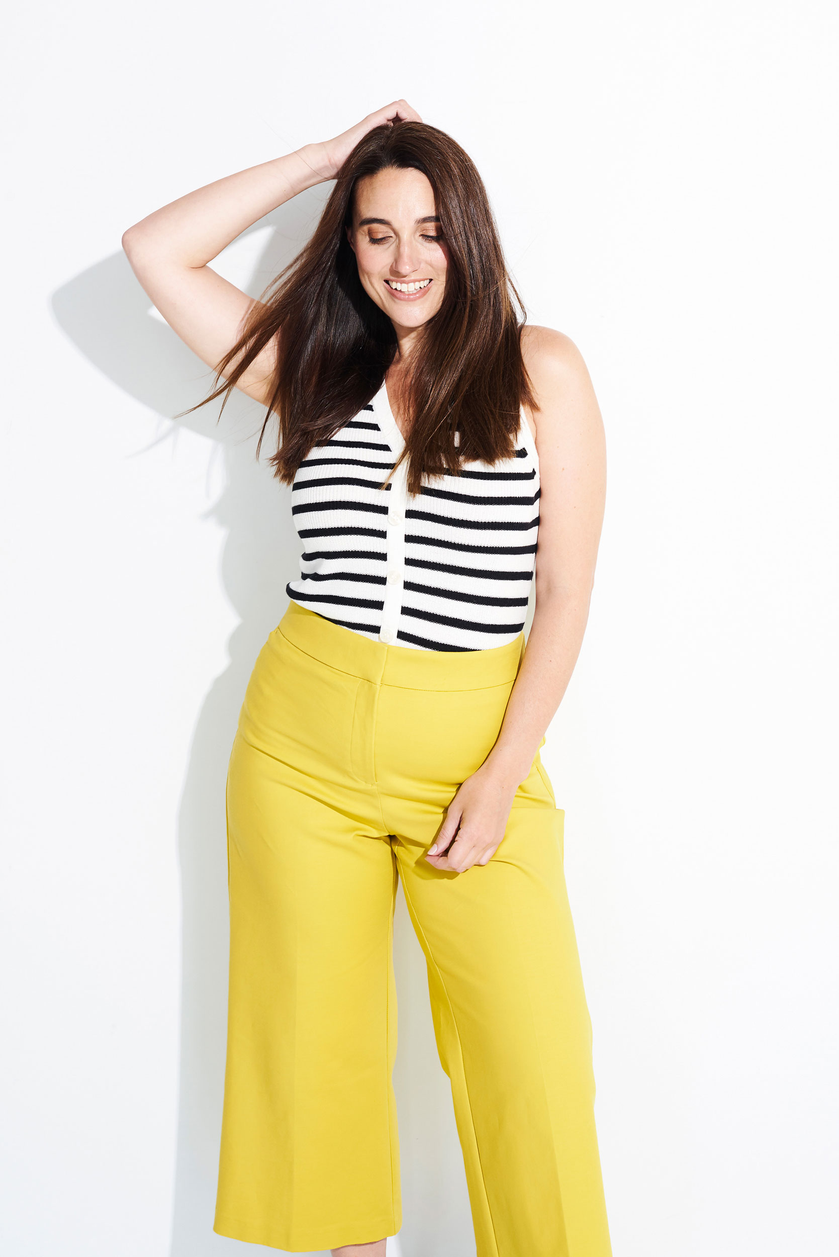 Brunette woman styled in striped top and yellow pants