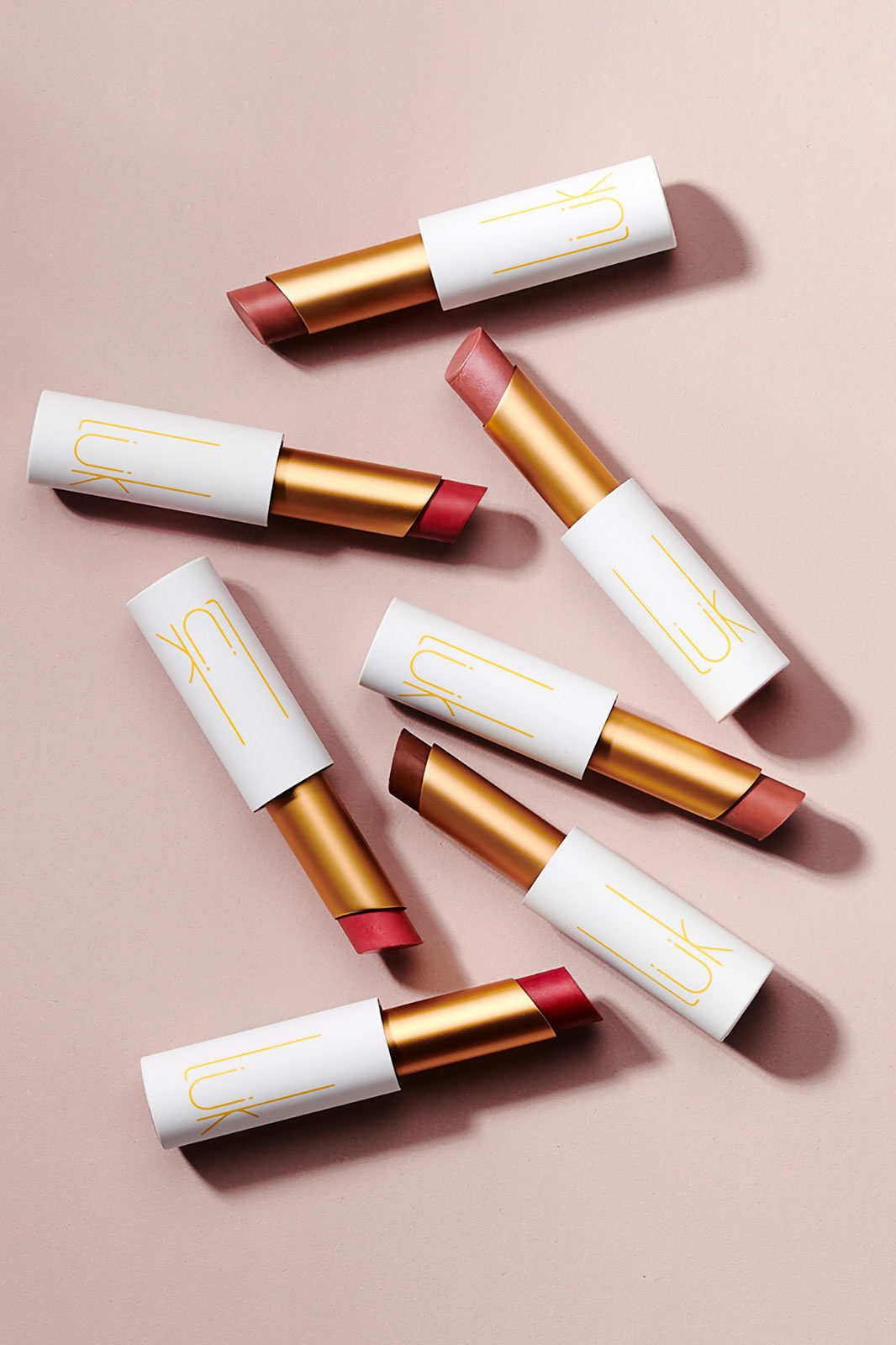 Seven tubes of lipstick on mauve surface