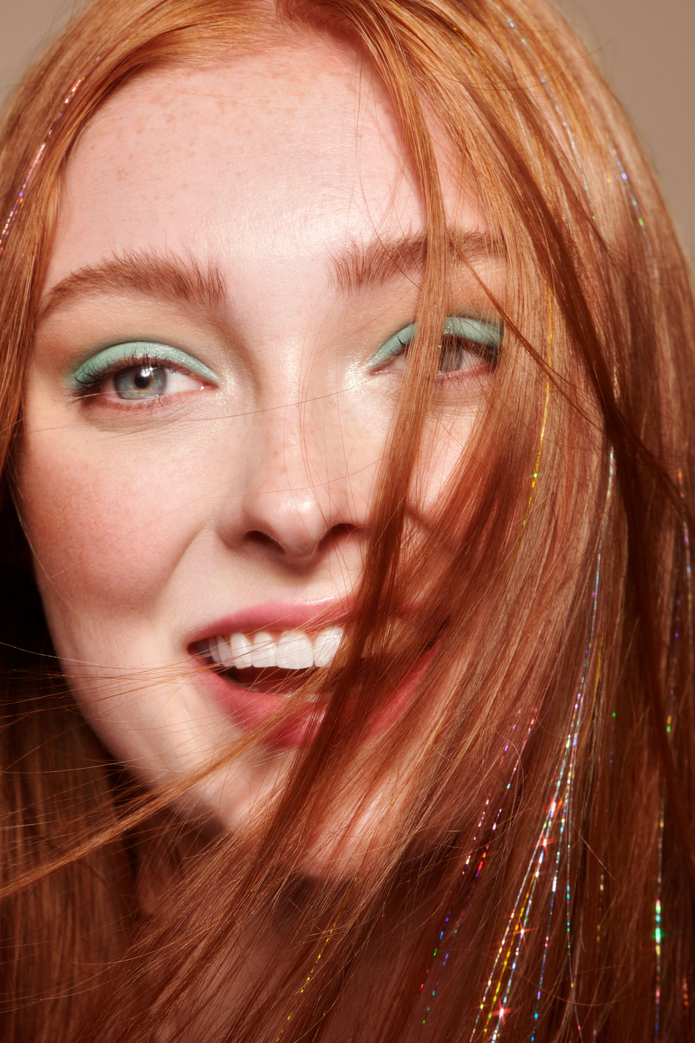Tight portrait of female model with tinsel-streaked red hair and mint eyeshadow