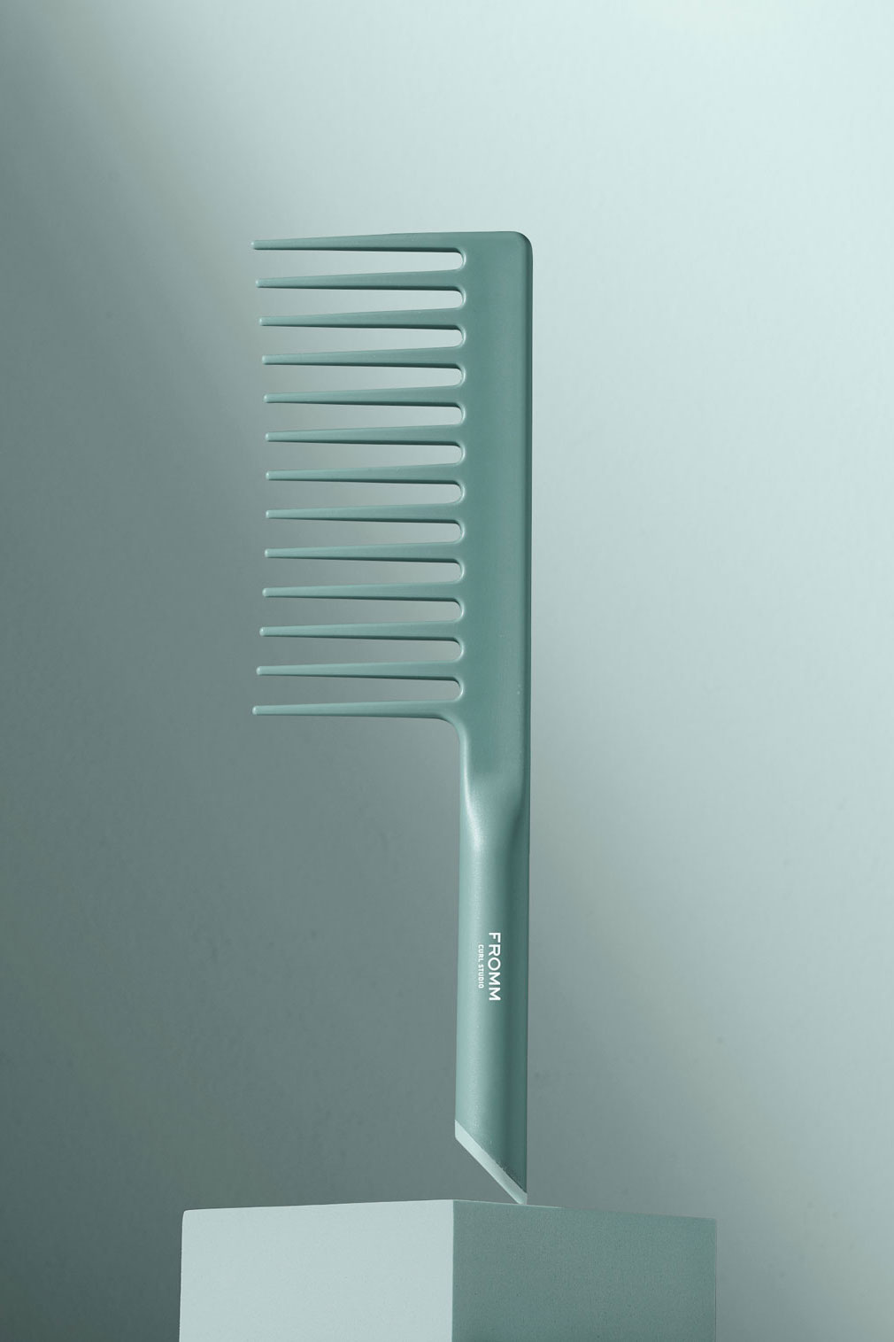 Mint green comb suspended on pedestal