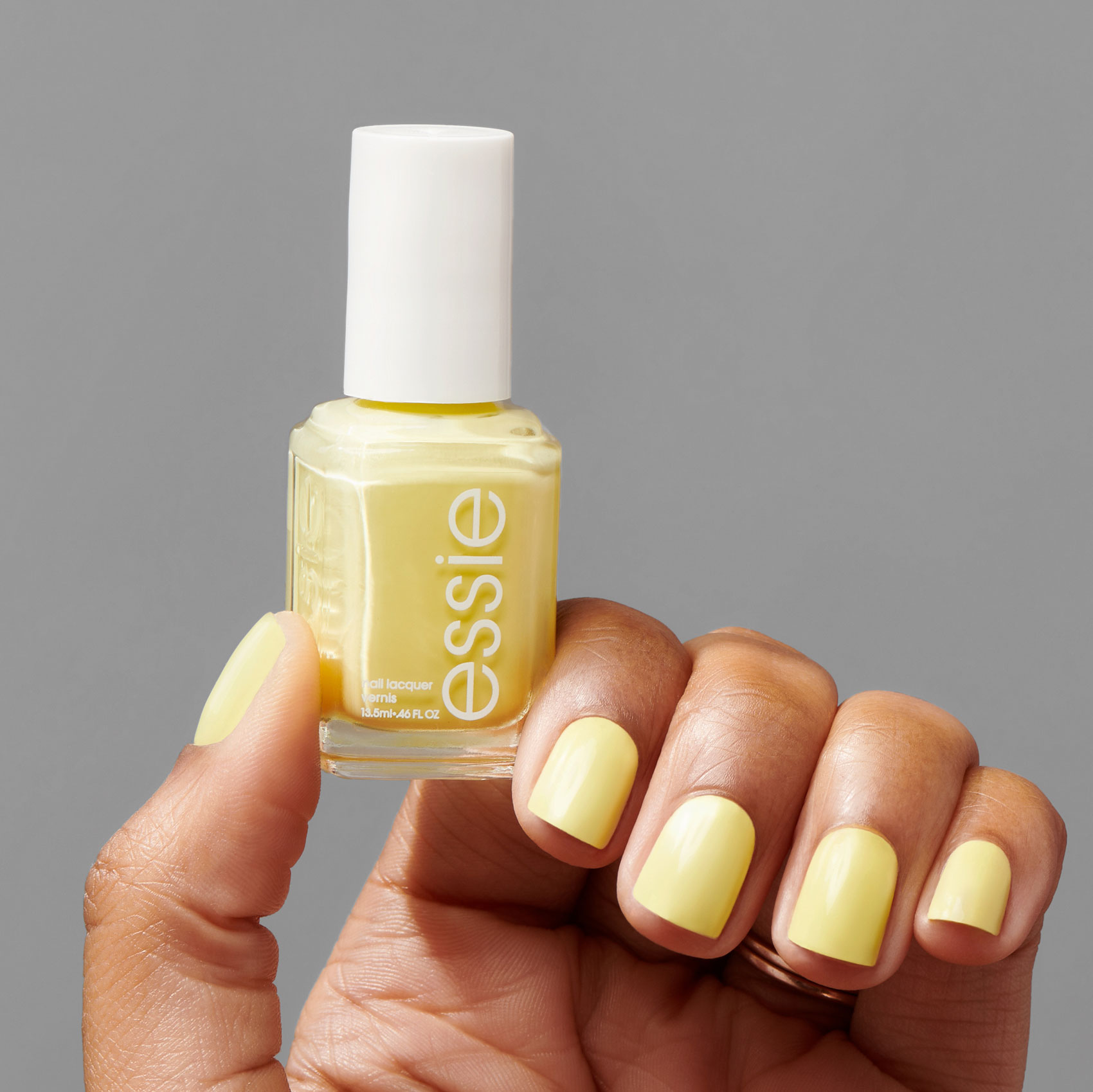 Female hand holding yellow nail polish bottle