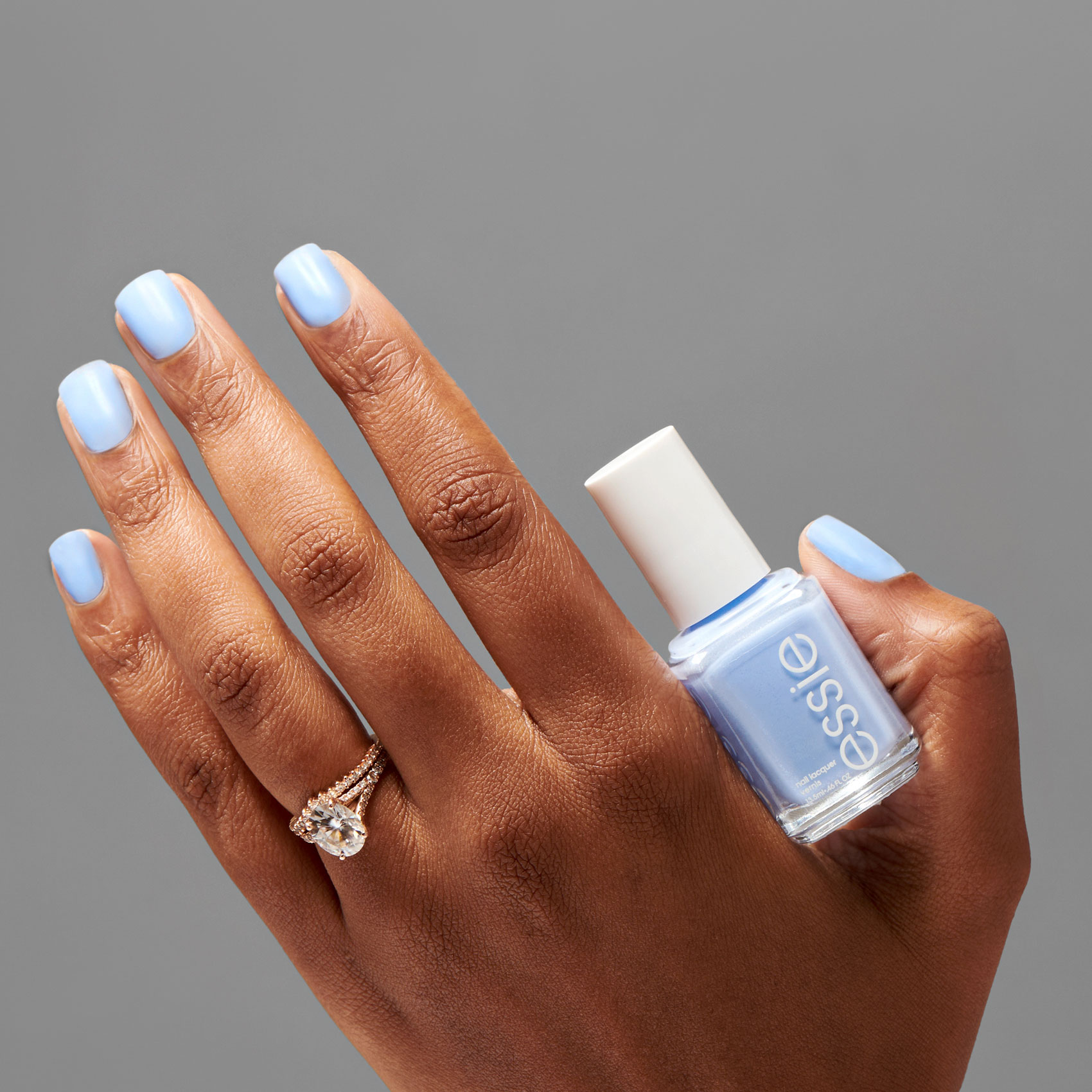 Female hand holding cornflower blue nail polish bottle
