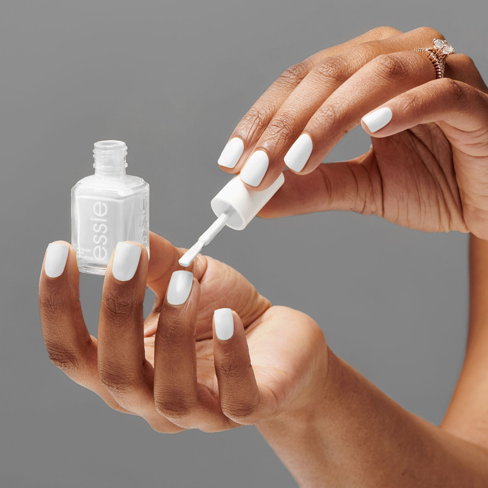 Female hands applying bridal-inspired white nail polish