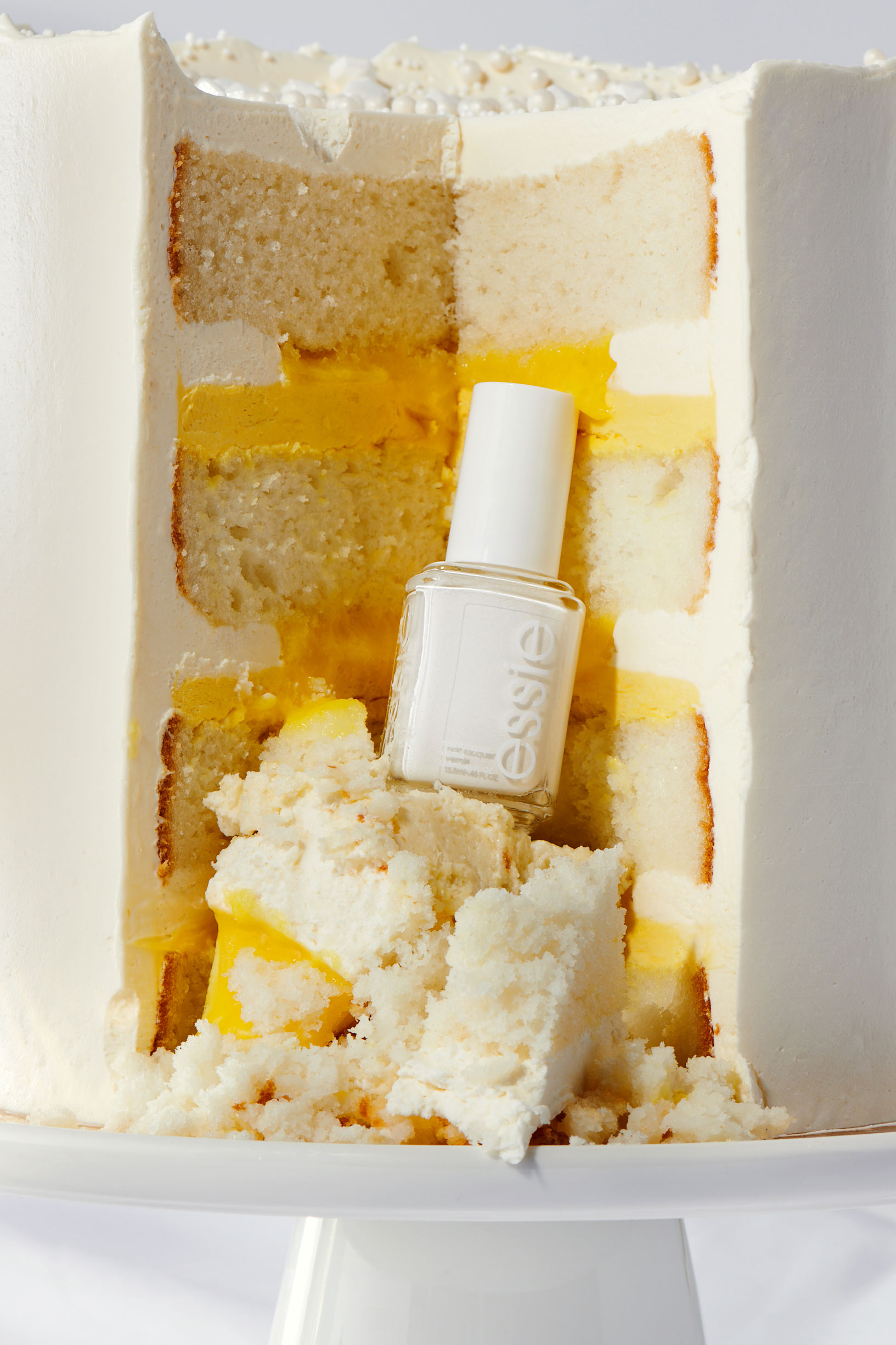 White nail polish bottle nestled in a sliced wedding cake