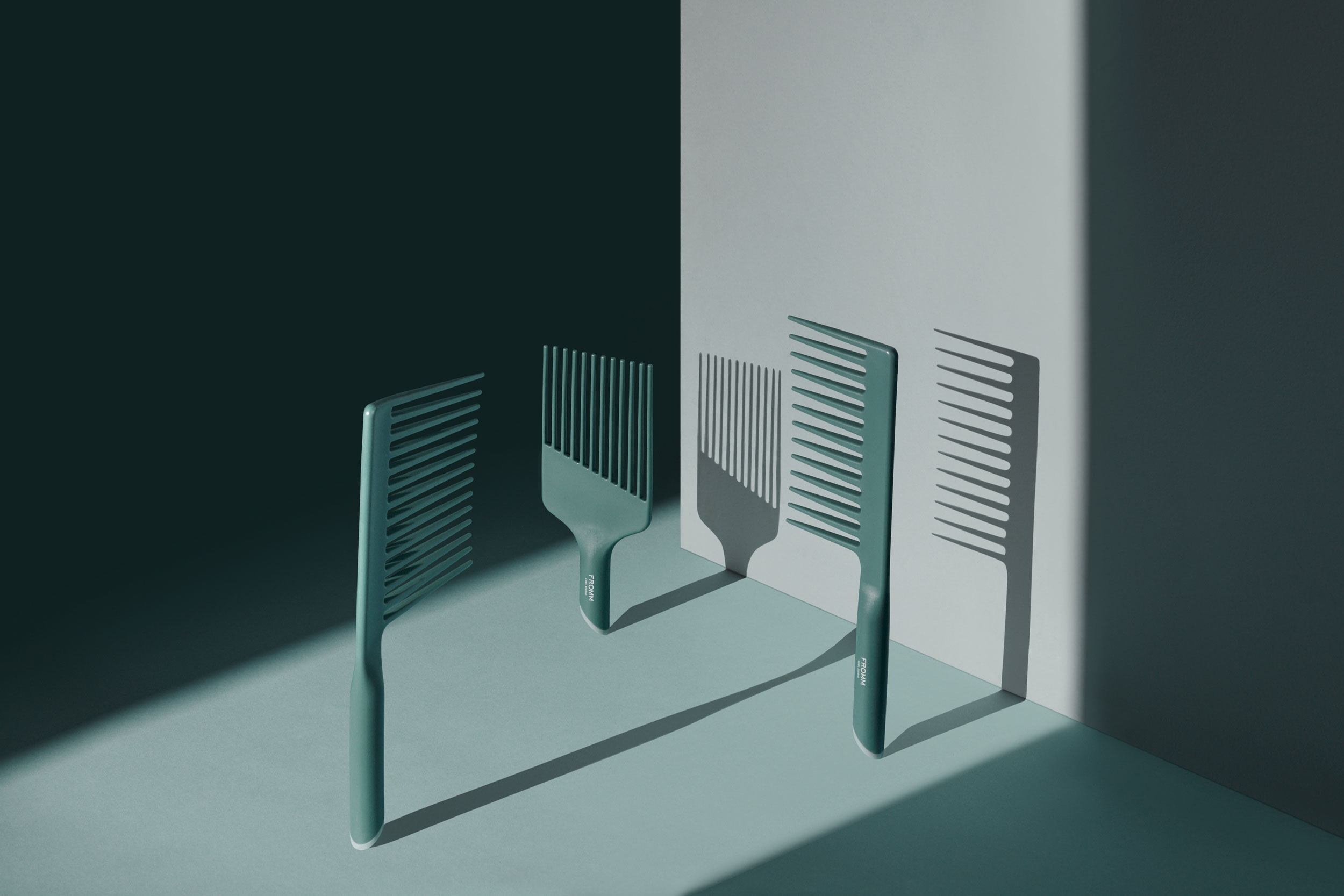 Trio of green combs suspended vertically and lit to cast a long shadow