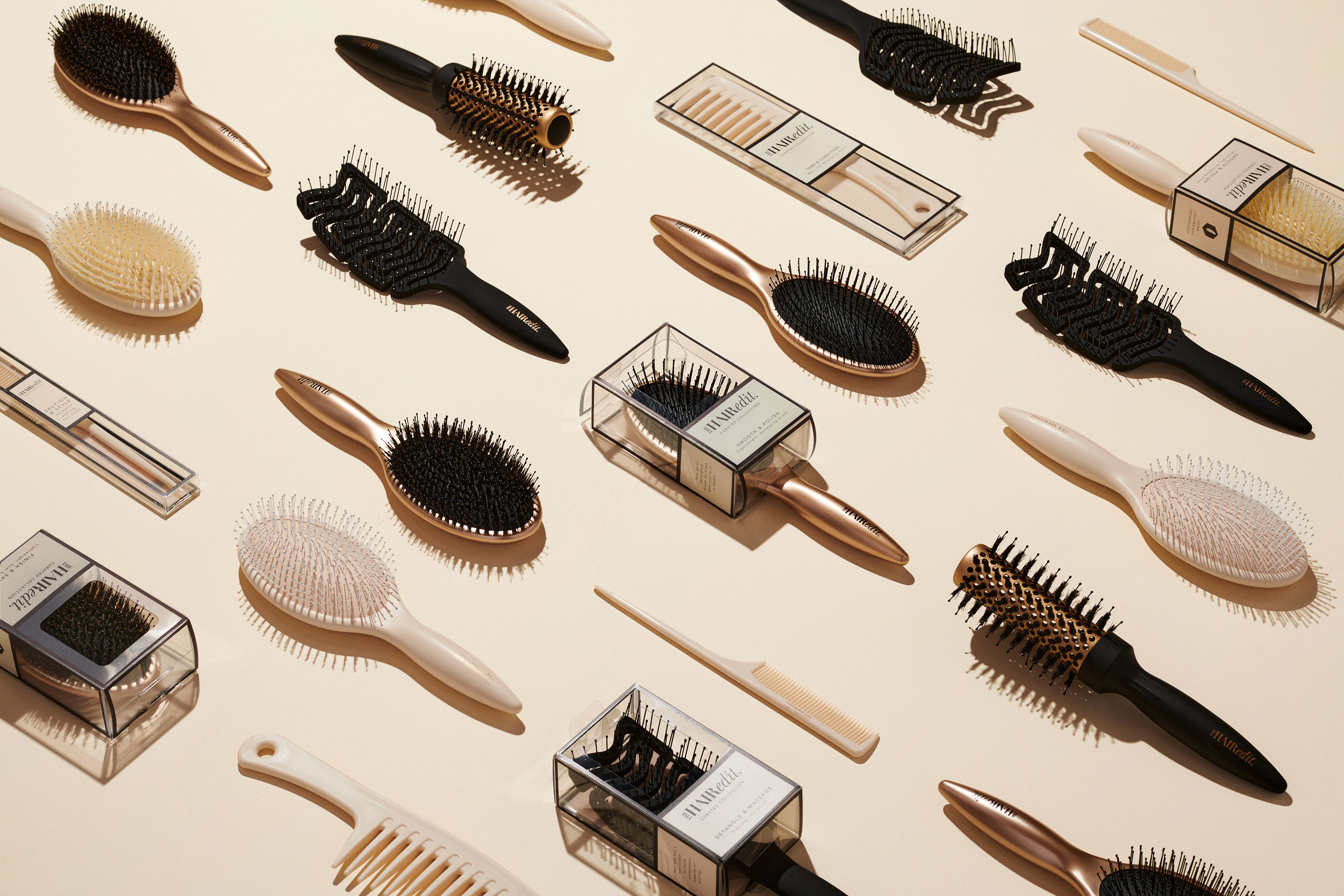 Hair brushes and combs organized neatly as flat-lay on cream-colored surface
