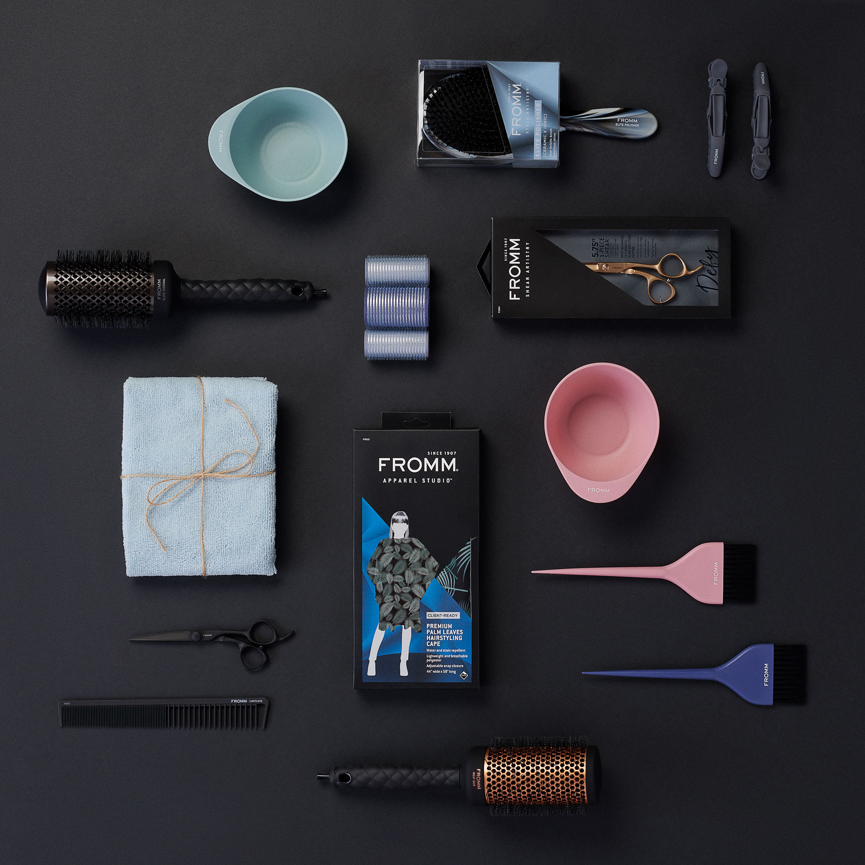 Hair styling tools organized neatly as flat-lay on black surface