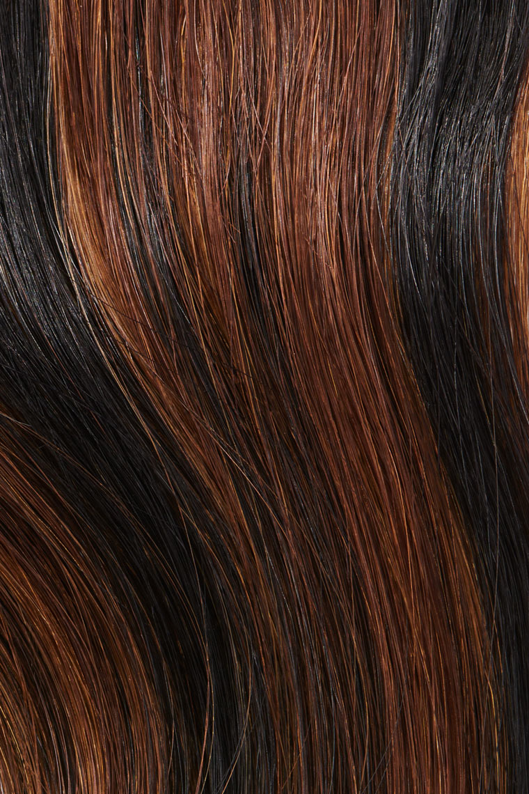 Texture image of black hair extension with auburn highlights
