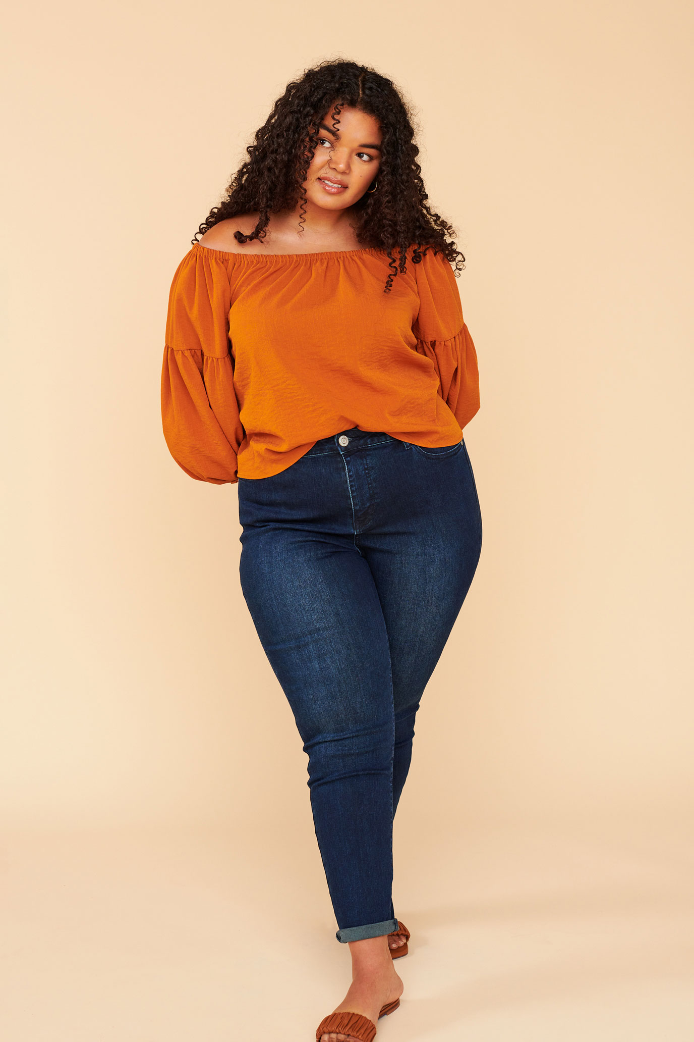 Woman wearing orange top, jeans and sandals