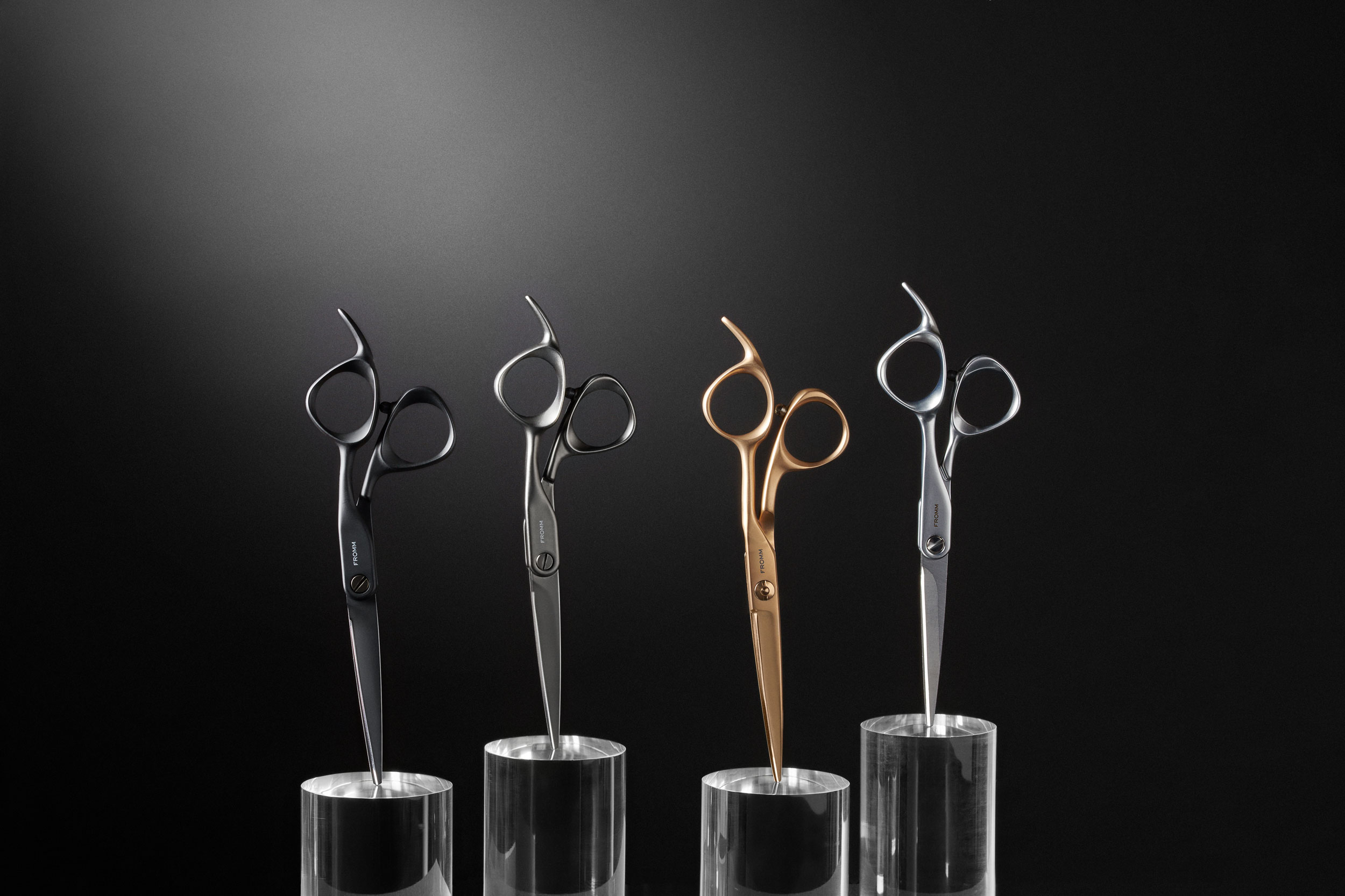 Four hair cutting sheers suspended on clear cylinders