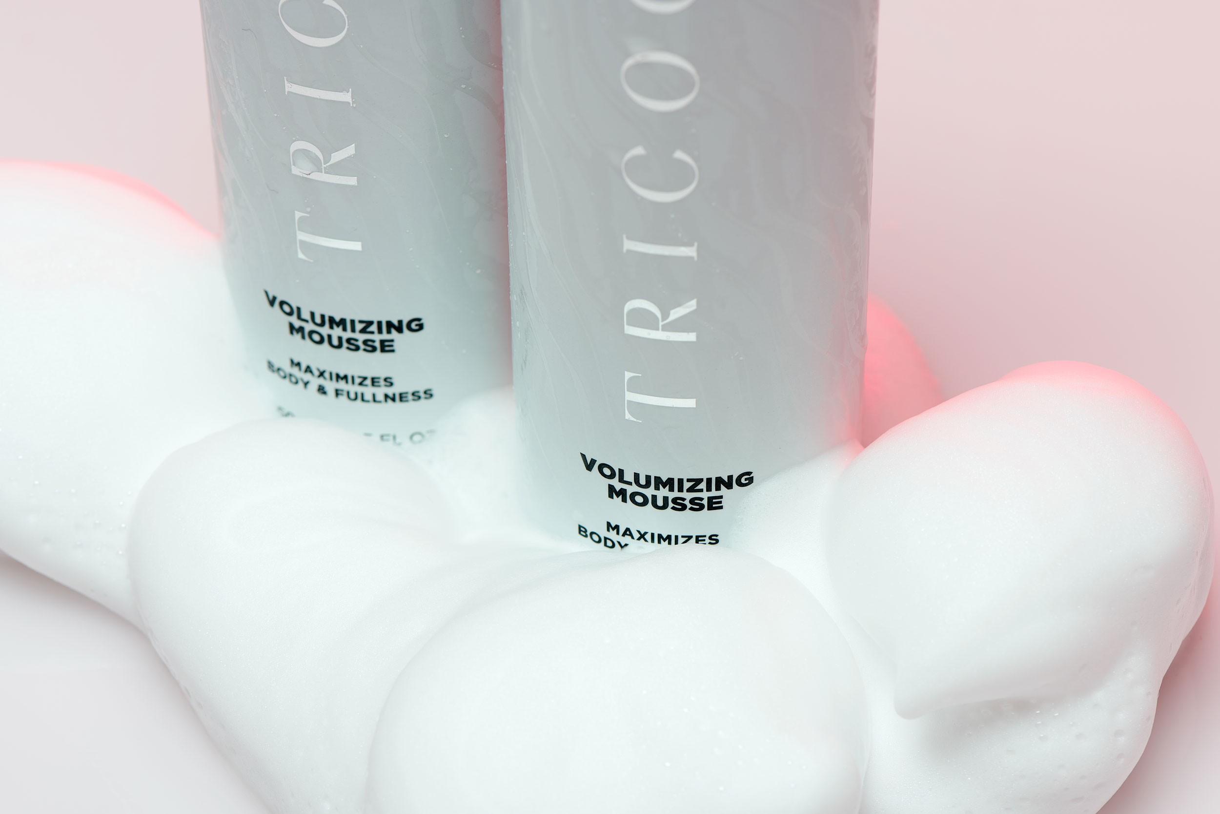 Detail image of two haircare products nestled in mousse
