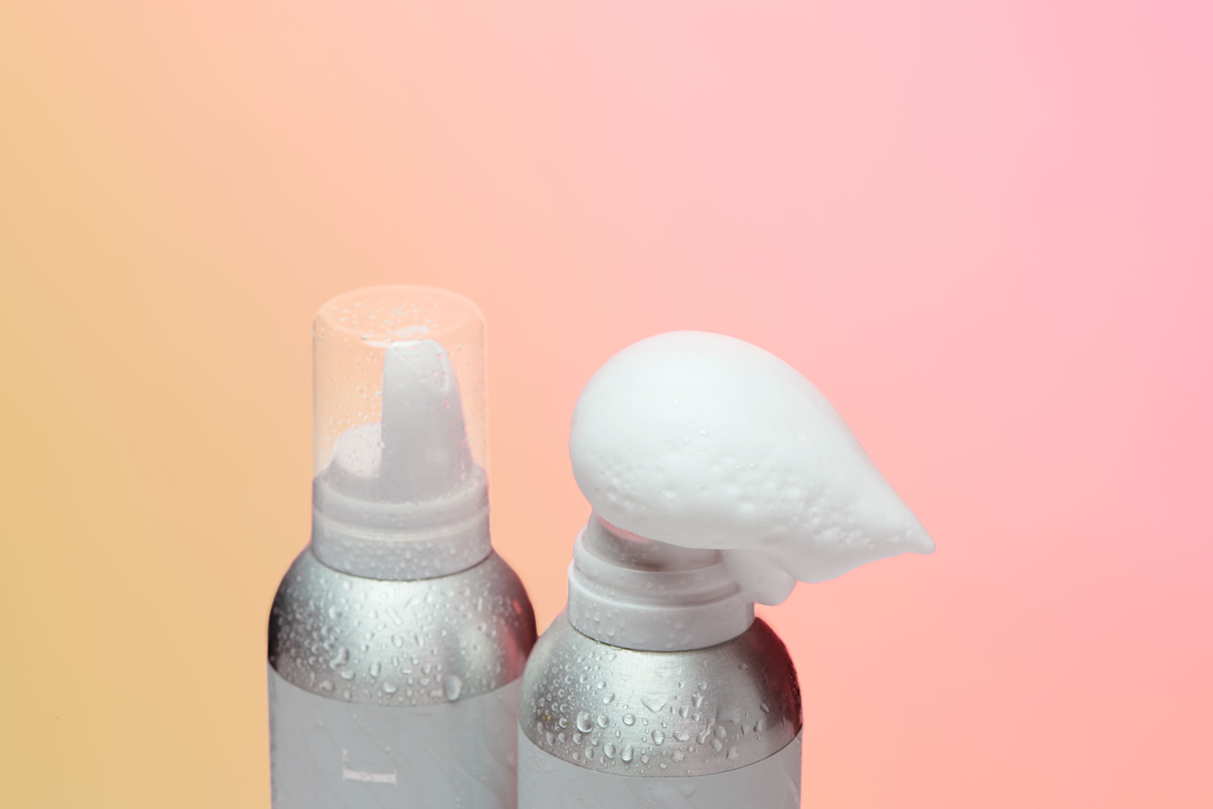 Two volumizing mousse products including one with mousse coming out of its container