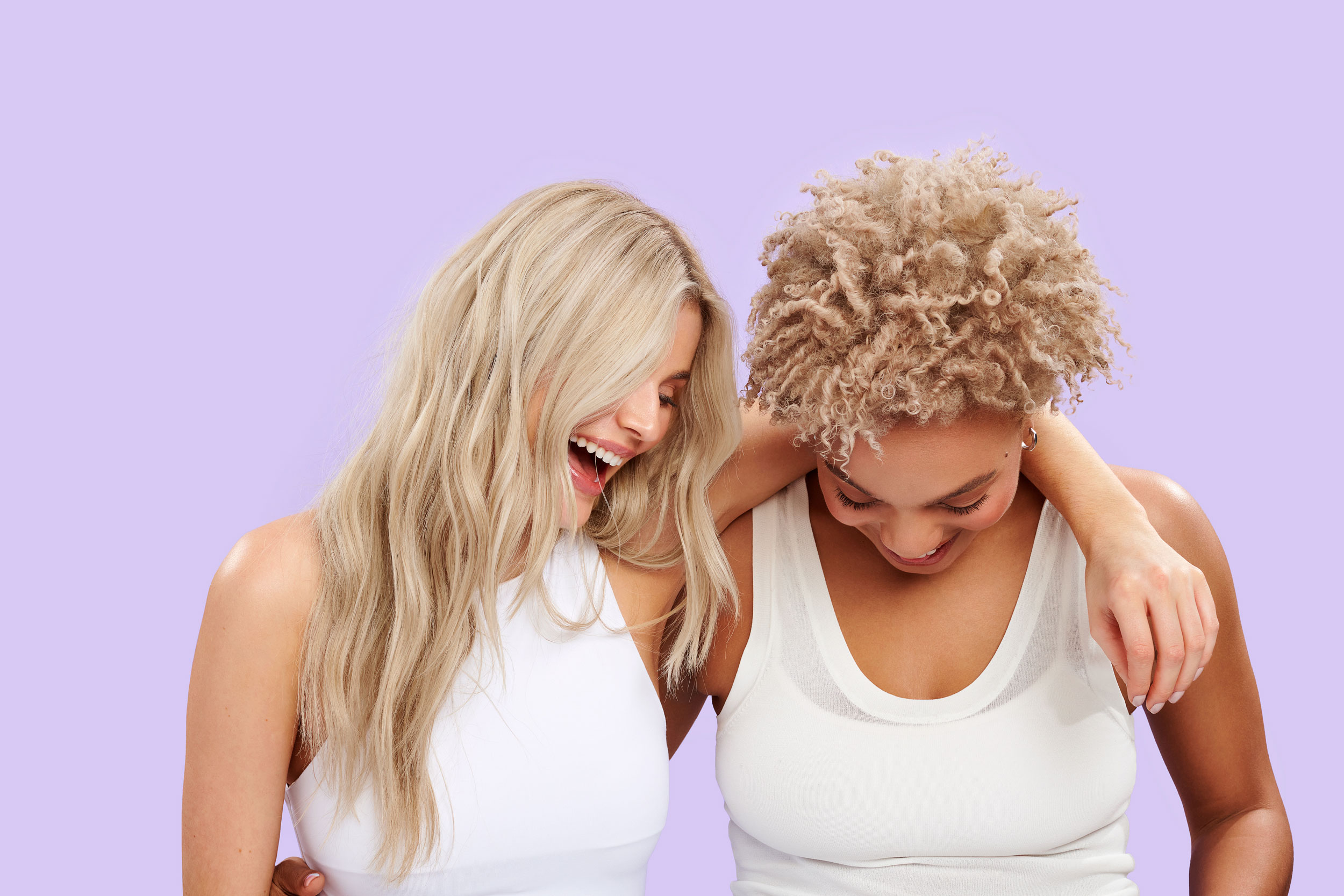 Two women laughing on purple background
