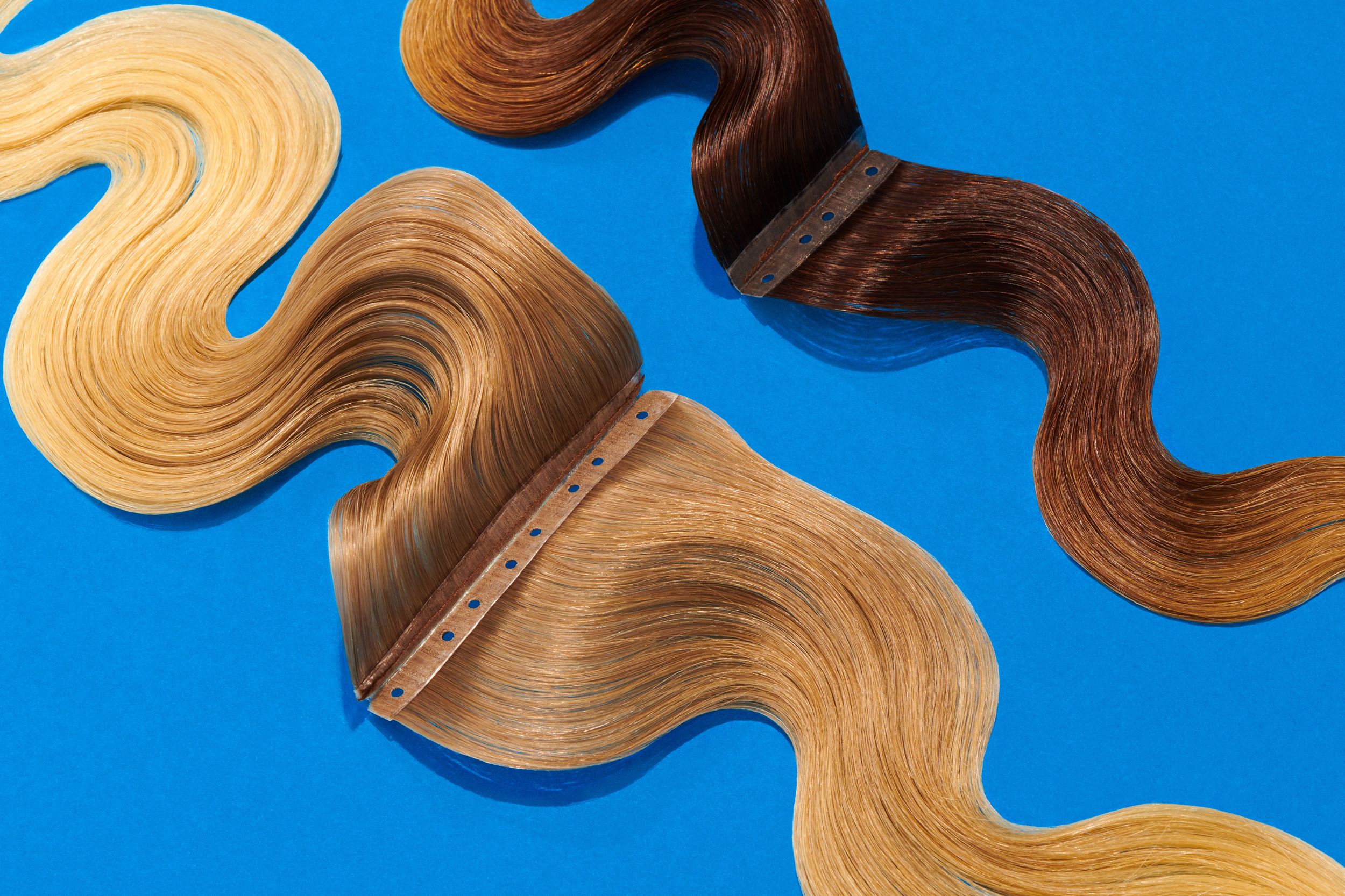 Balayage-style hair extension wefts on blue background