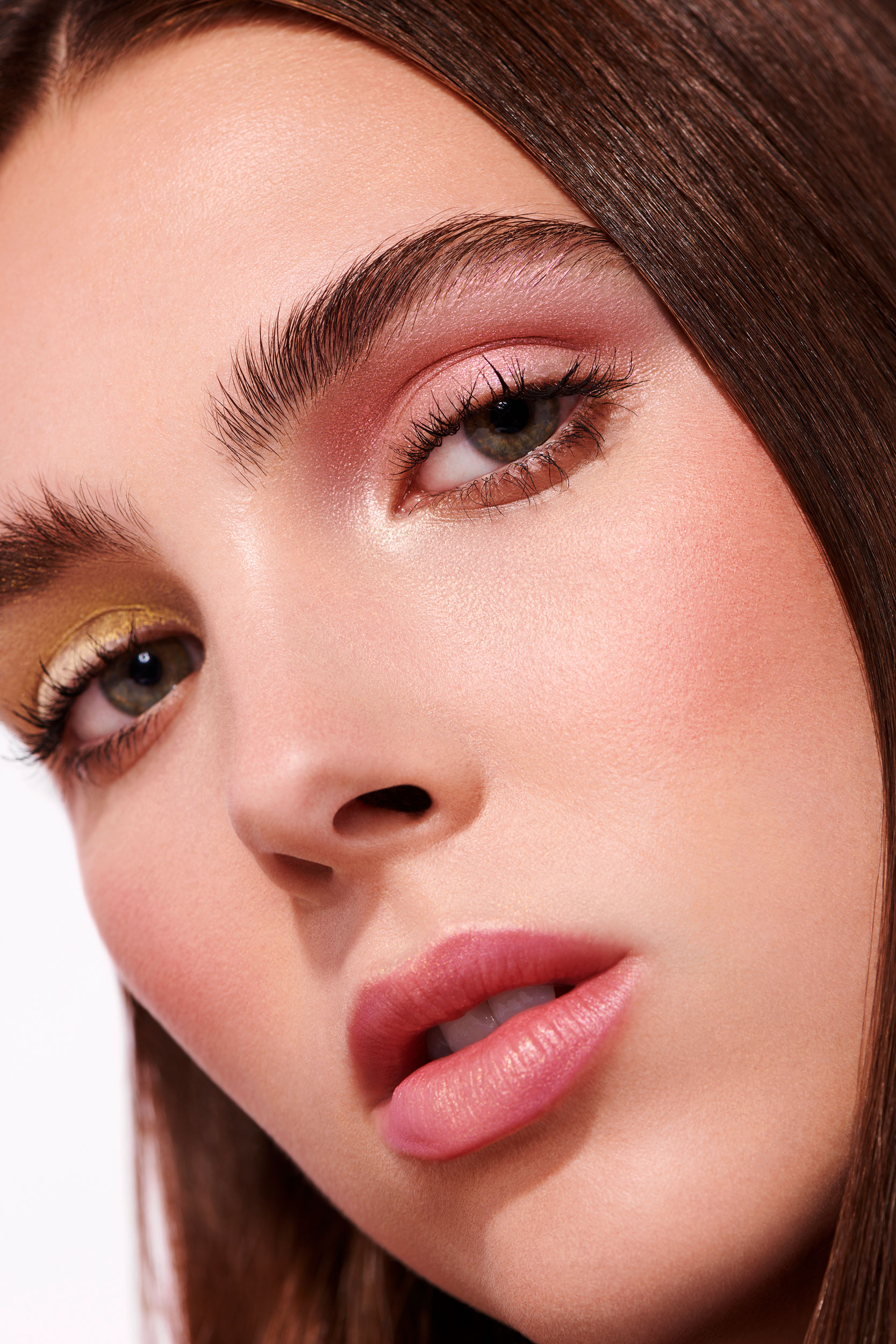 Tight portrait image of brunette female with pink and gold shimmer on eyelids