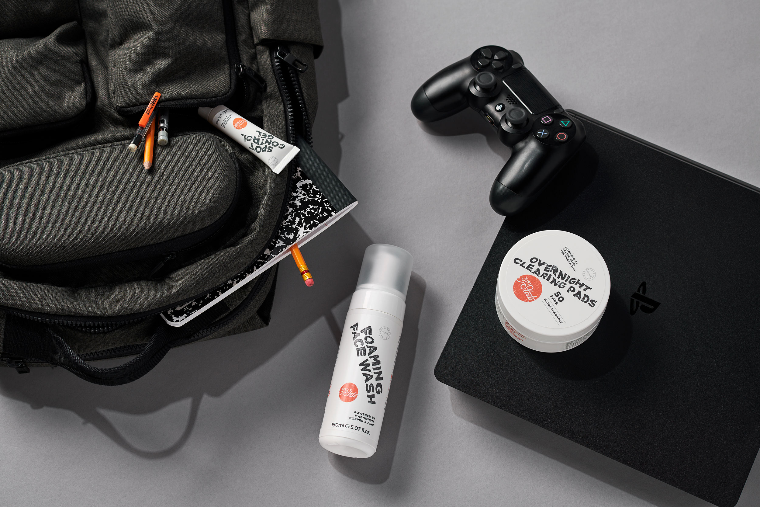Lifestyle image displaying skin care products amongst backpack, school supplies and game console