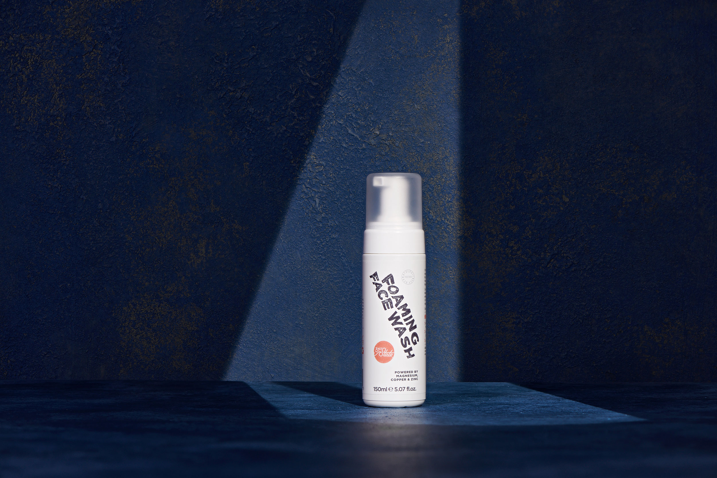 Face Wash skin care product with framed lighting on blue, textured surface