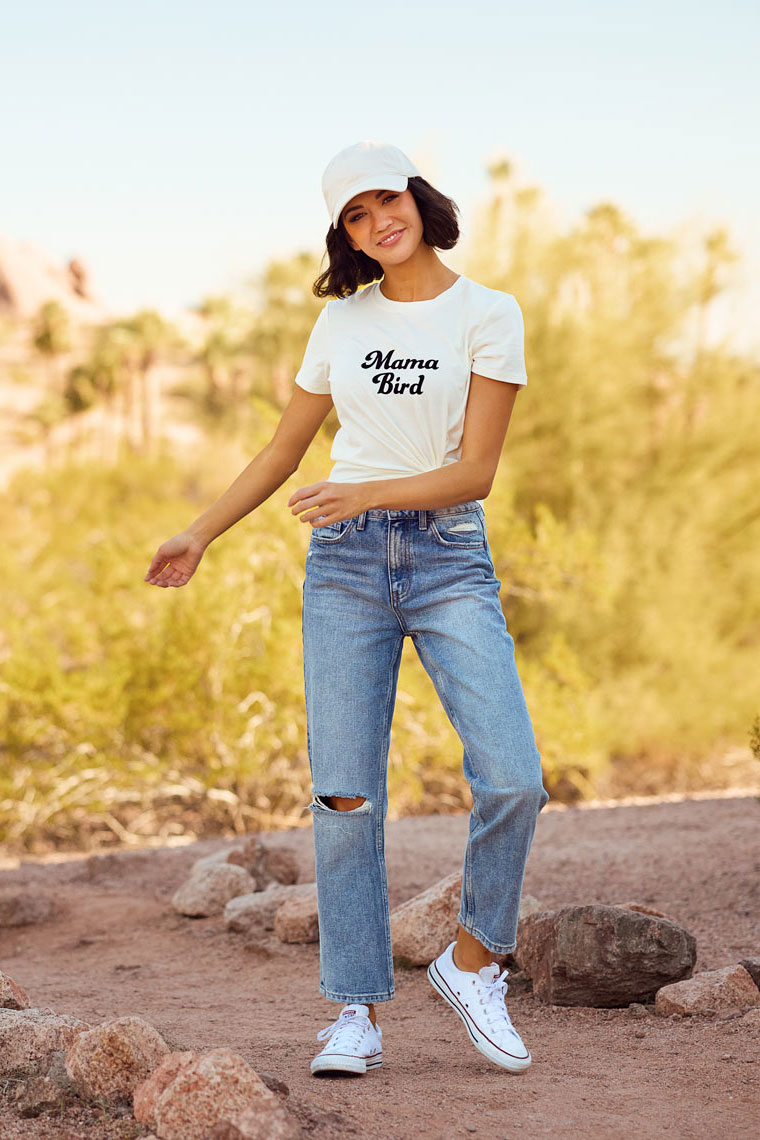 Brunette female in white t-shirt, jeans and baseball cap